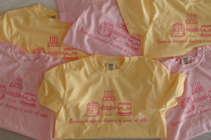 Yellow and pink shirts with cake design and text "Because everyone deserves a piece of cake"